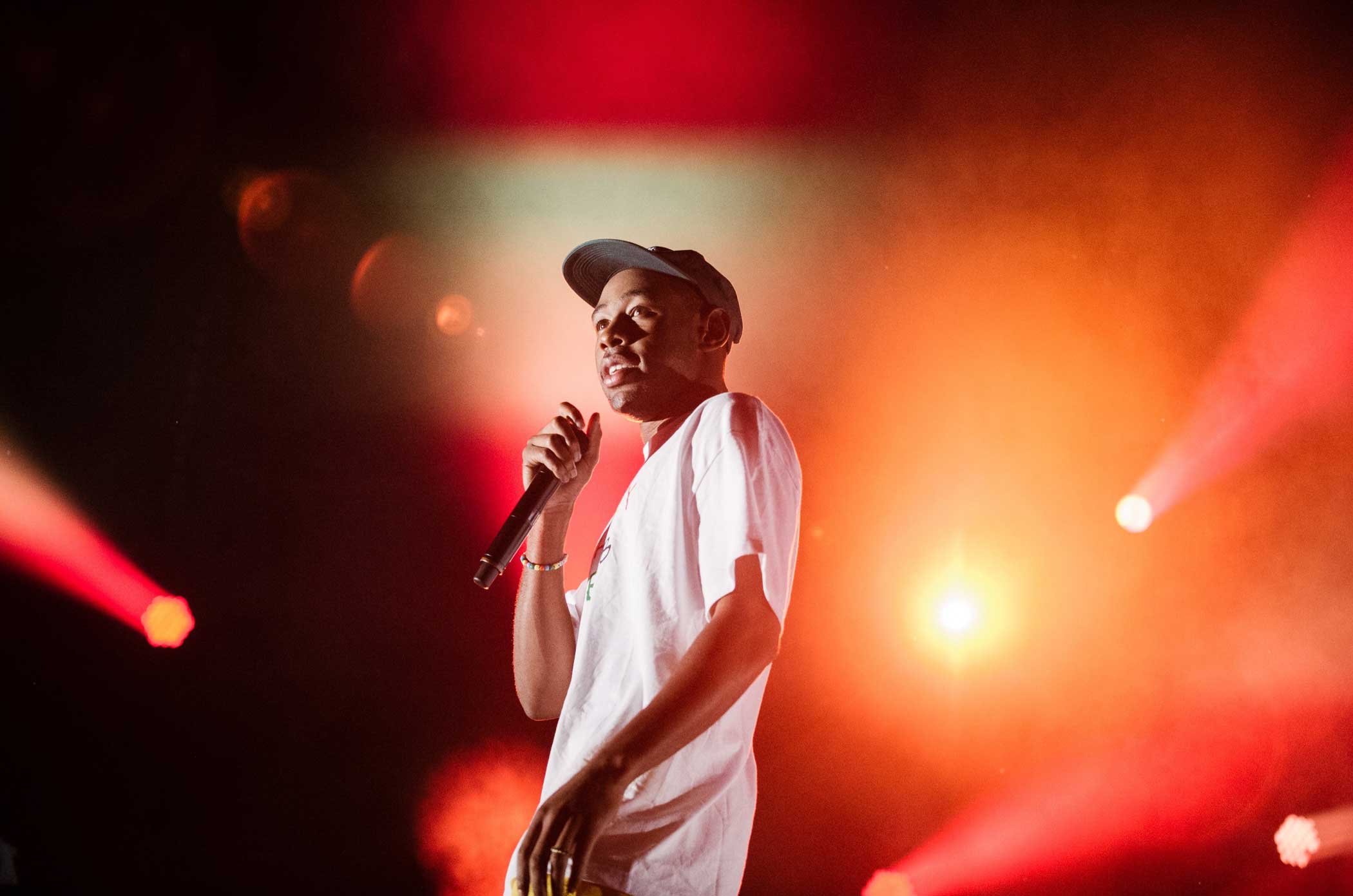 Tyler the Creator performs against a backdrop of red lights. 