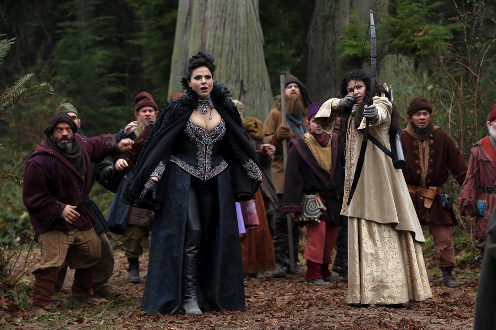 The Evil Queen, The Dwarfs, and other fairytale characters all cower in fear against an unseen foe as Snow White points her arrow at it in the Enchanted forest.
