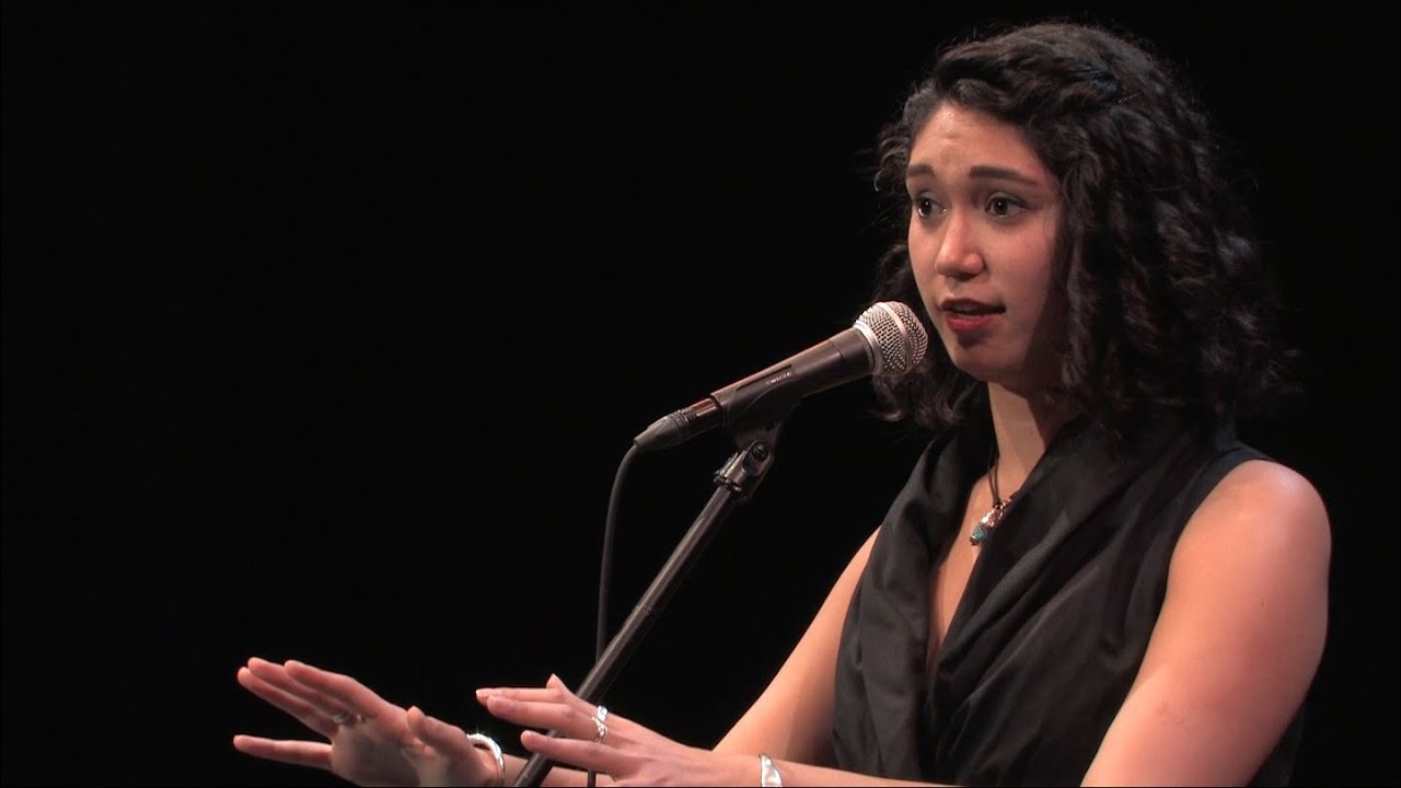 Photograph of poet Sarah Kay delivering spoken word poetry onstage. 