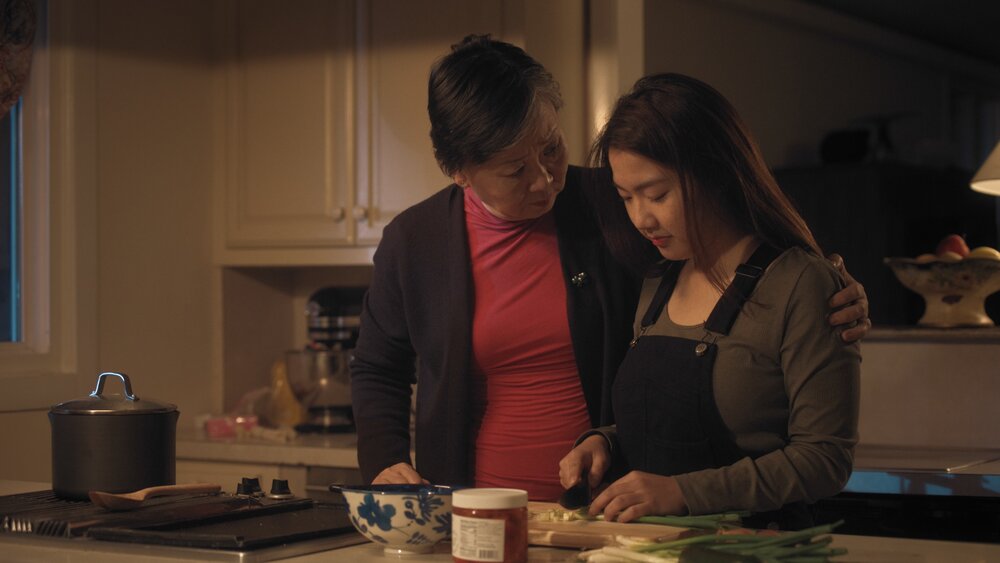 Parked in America; Jamie cutting vegetables with her grandma's arm around her shoulder