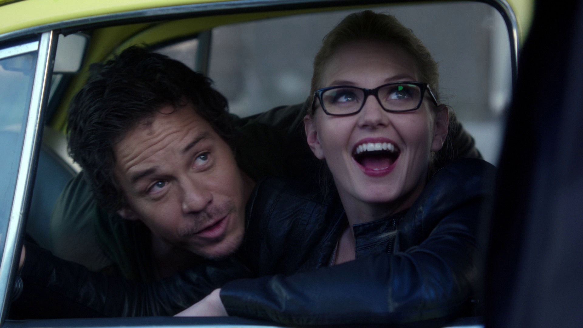 Emma Swan and Neal Cassidy are smiling and talking to an unseen officer in their stolen car.
