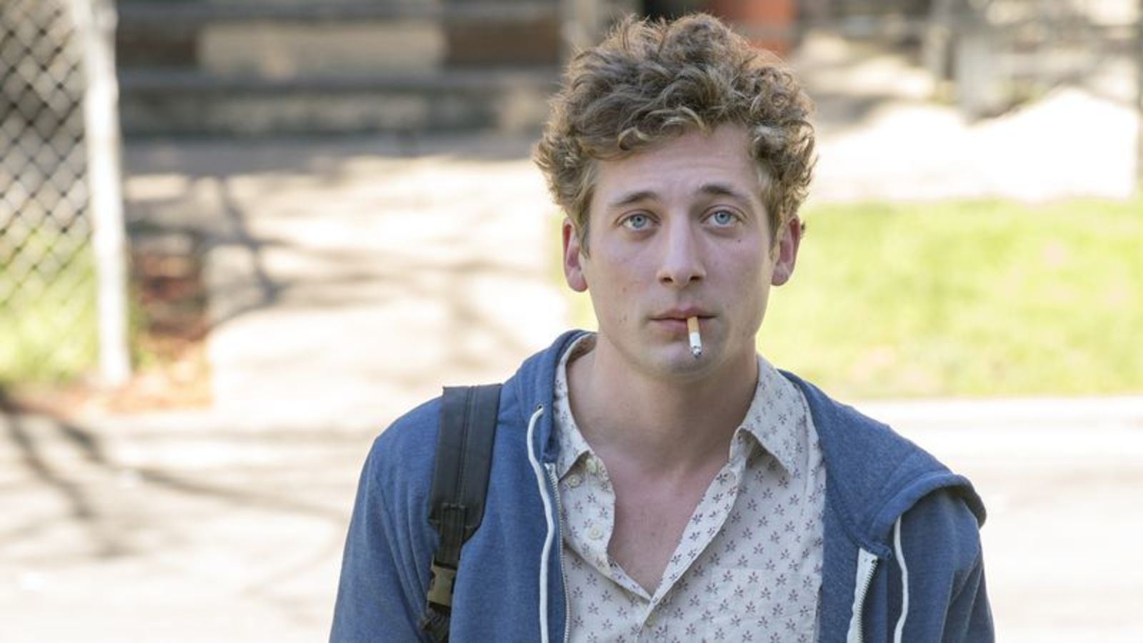 Lip Gallagher is smoking a cigarette and looking up intensely. 