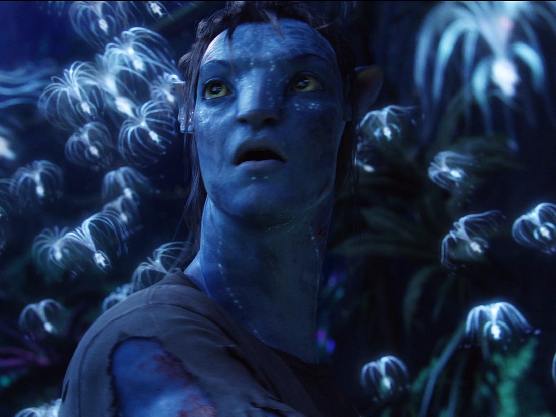 Jake Sully (in Avatar form) is surrounded by small, floating, bug-like creatures in James Cameron's 'Avatar,' 2009.