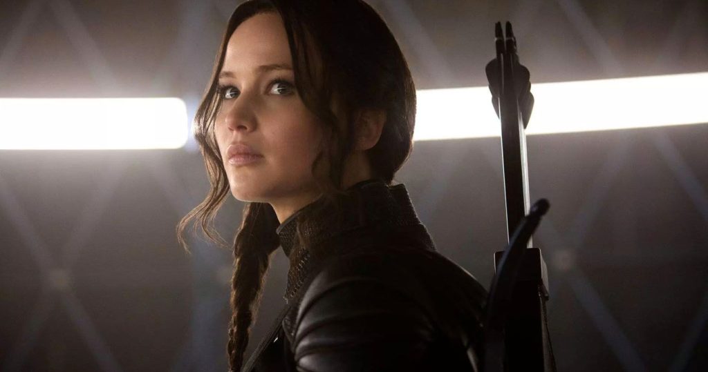 Katniss Everdeen prepares for the Hunger Games with a bow and arrow on her back, and a solemn look upon her face. 
Gary, Ross, dir. The Hunger Games. 2012.