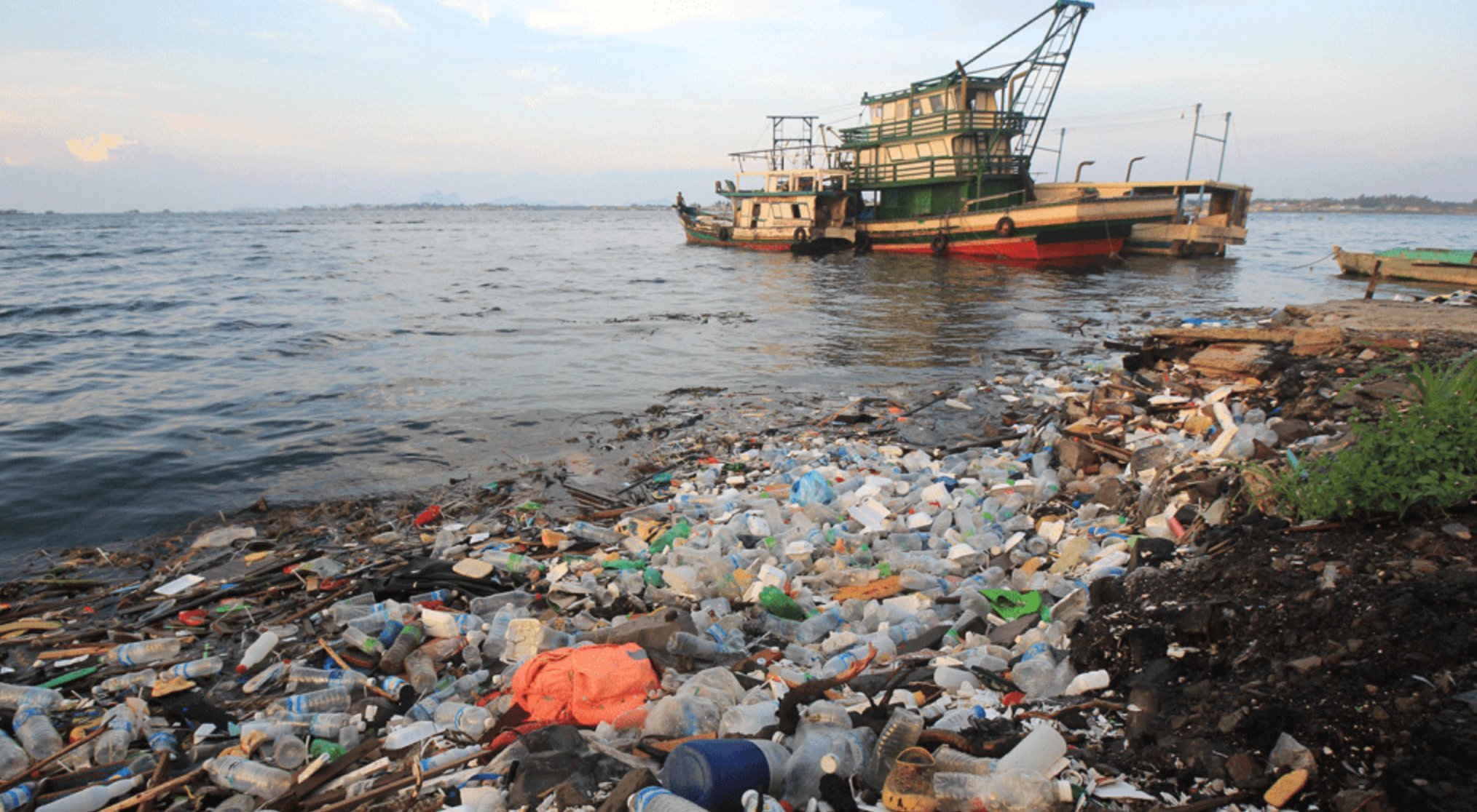 Shot by Kip Andersen's team, a fishing boat sets off to sail as plastic litters the ocean shore. 