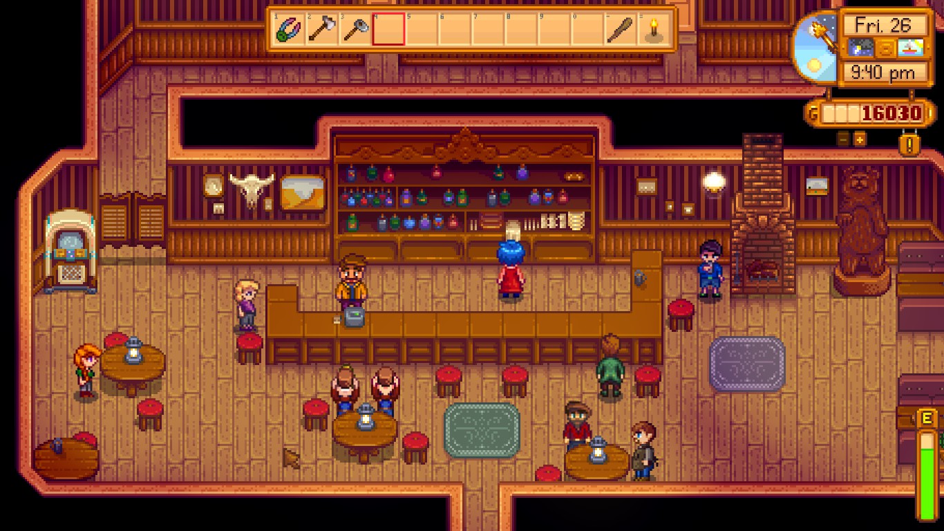 The main room of the Stardrop Saloon, a bar in Pelican Town. It is a large room made mostly of warm wood. A large counter dominates the middle of the back wall, and a few round tables are strewn about in front of it. There are a variety of characters in the saloon, most notably Pam, a white blonde woman in a purple shirt, and Shane, a white man with dark hair in a blue hoodie. Both are severe alcoholics suffering from depression.