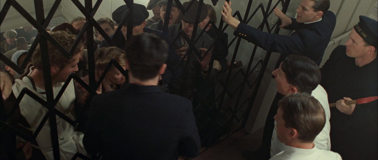 Passengers in th 1997 Titanic film, are trying to push their way through locked gates but the crew members are guarding the gates on the other side.