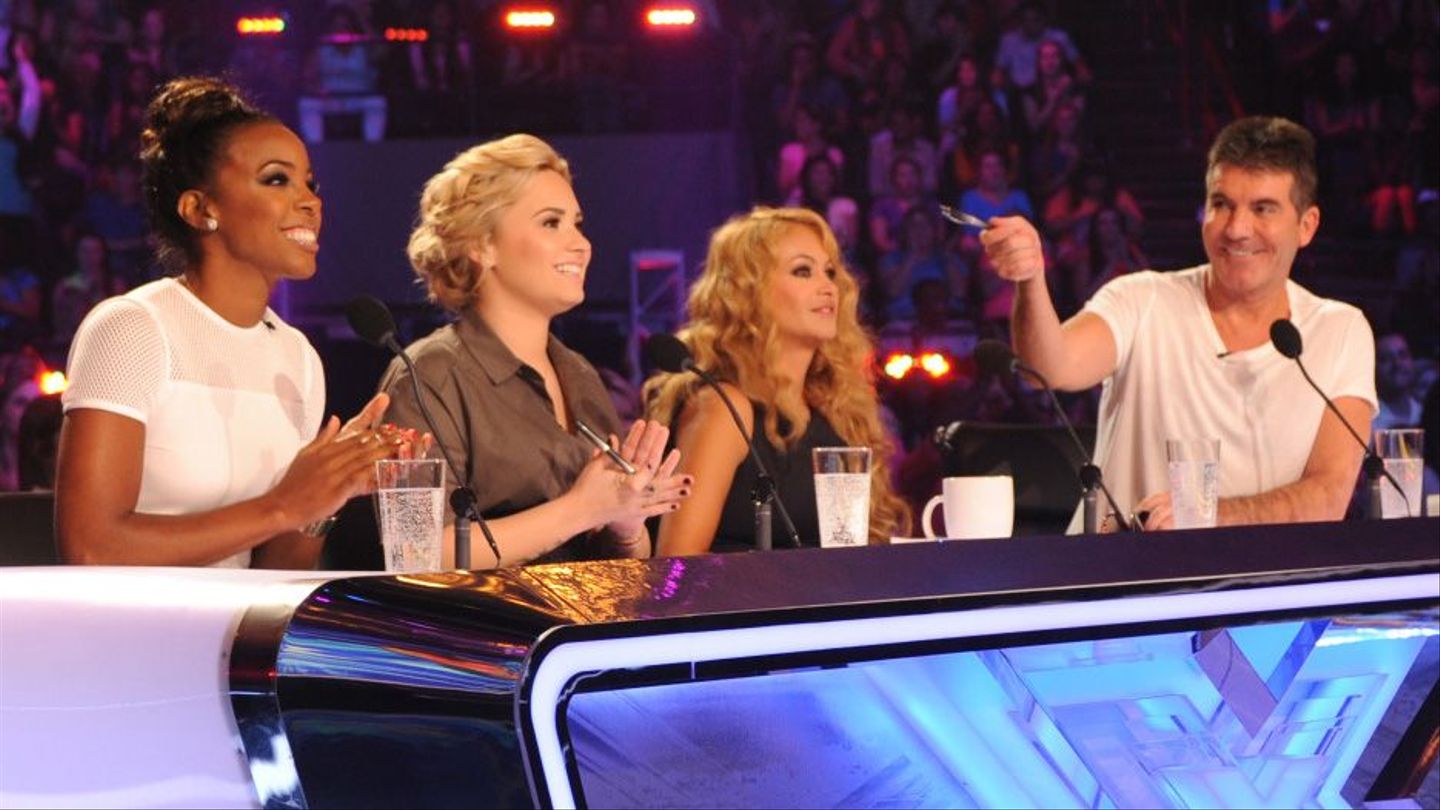 Demi Lovato sitting with her fellow judges on The X Factor panel. 