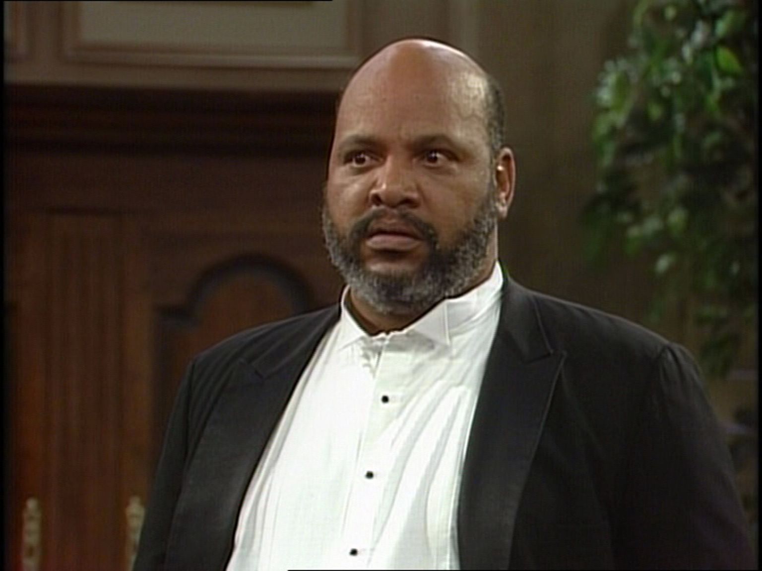 Philip Banks, or Uncle Phil, stares intently off-screen. He has a salt-and-pepper beard and is wearing a black sport coat over a white shirt.