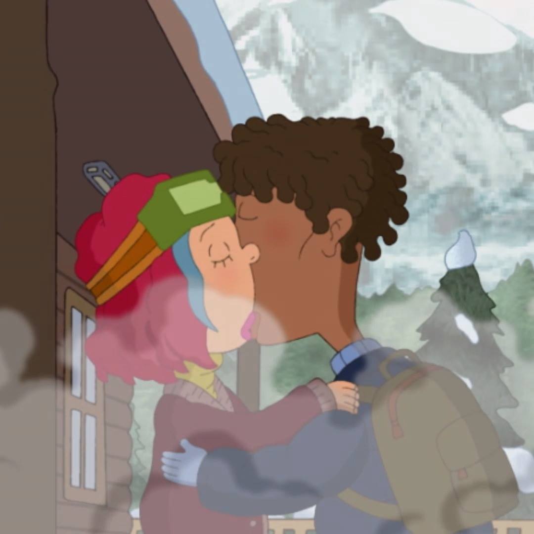 Ginger and Darren share a romantic kiss outside of a train station in the winter.