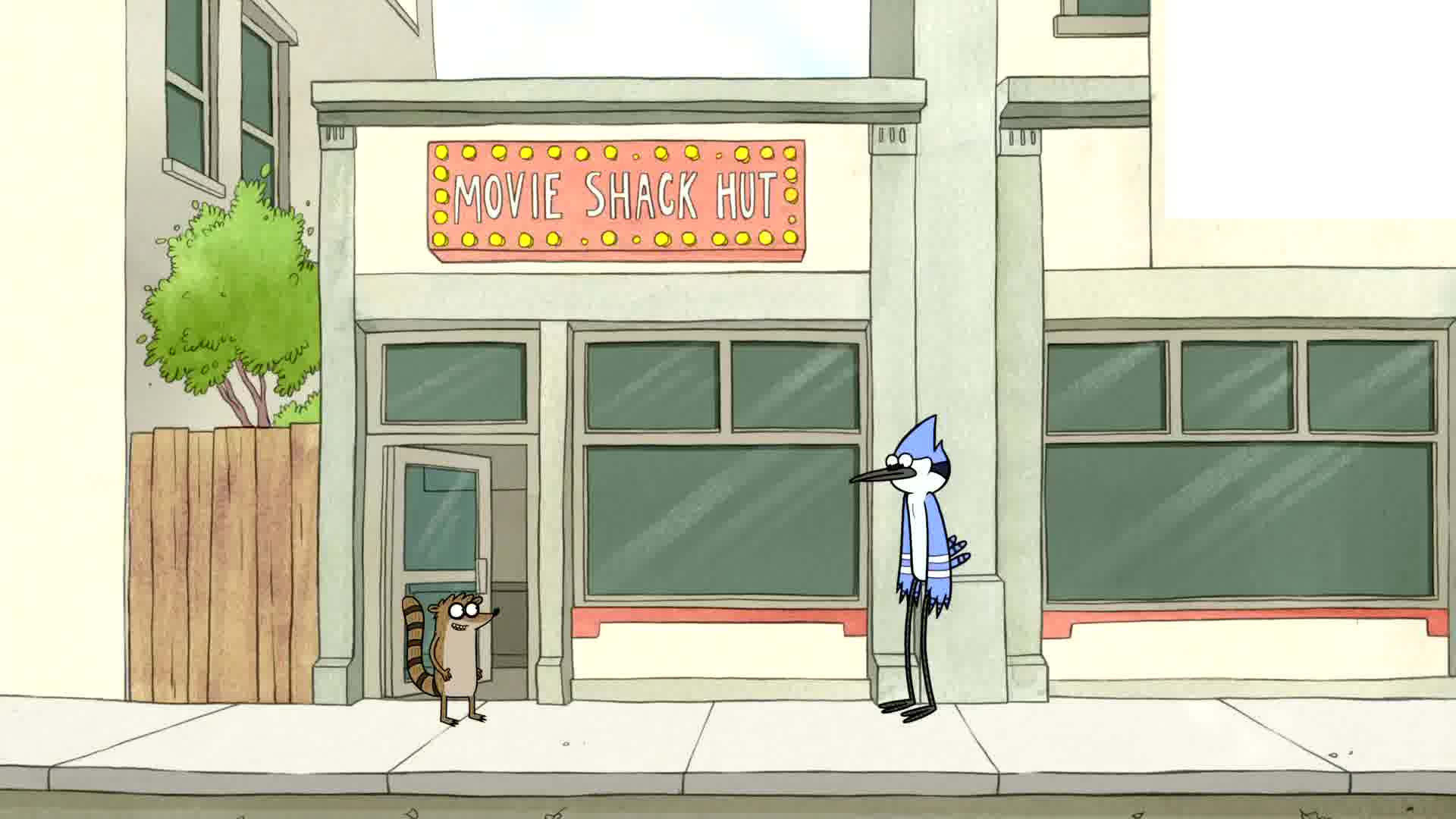 Mordecai and Rigby stand outside of a video rental shop. 