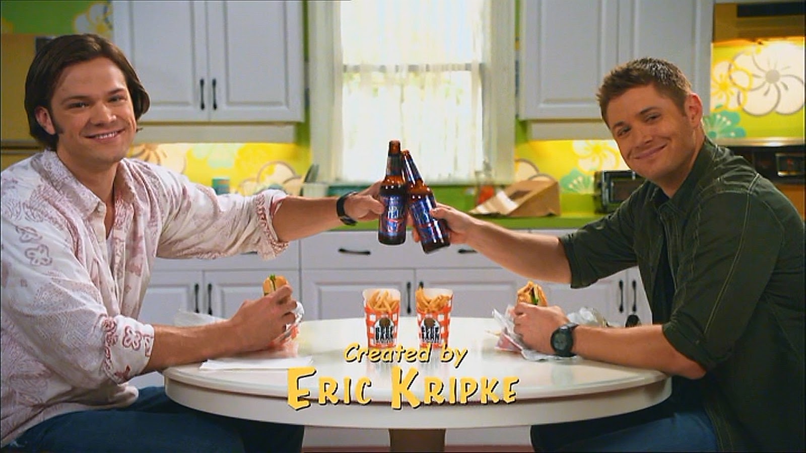 Sam and Dean toasting with a beer as their sitcom song ends at the beginning of the episode.