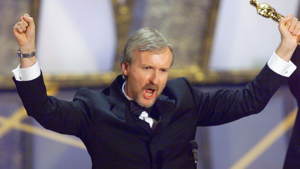 James Cameron holds his fists in the air, with his left hand clenching his oscar, after winning at the 1998 Academy Awards.