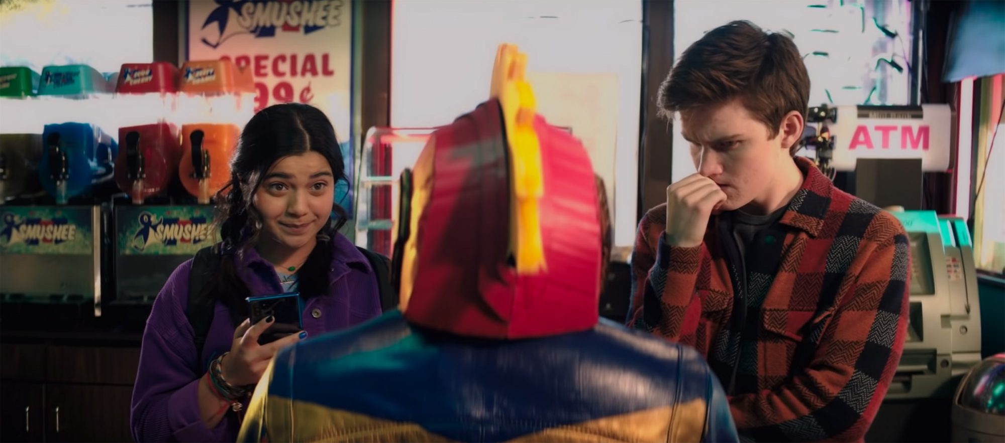 Iman Vellani as Kamala Khan and Matt Lintz as Bruno Carrelli looking at a Captain Marvel bike helmet in the gas station in Ms. Marvel (2021).