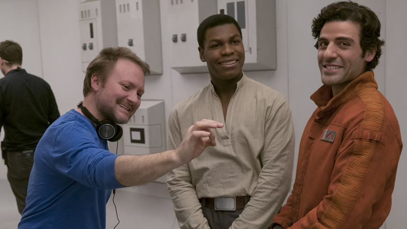 On the set of The Last Jedi, director Rian Johnson discusses something with actors John Boyega and Oscar Isaac. 