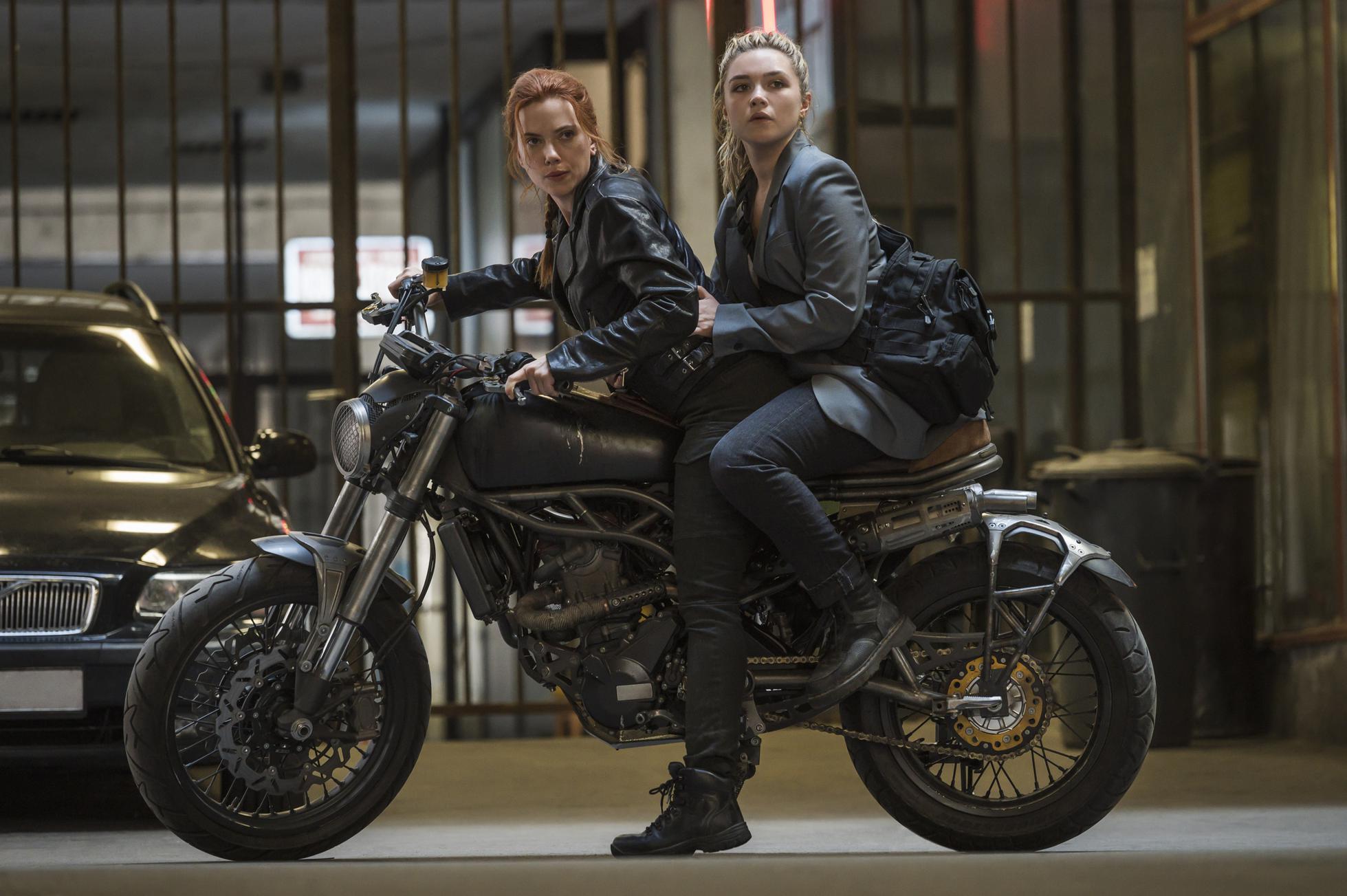 Scarlett Johansson as Natasha Romanoff and Florence Pugh as Yelena Belova riding a motorcycle in the streets of Budapest from Black Widow (2021).