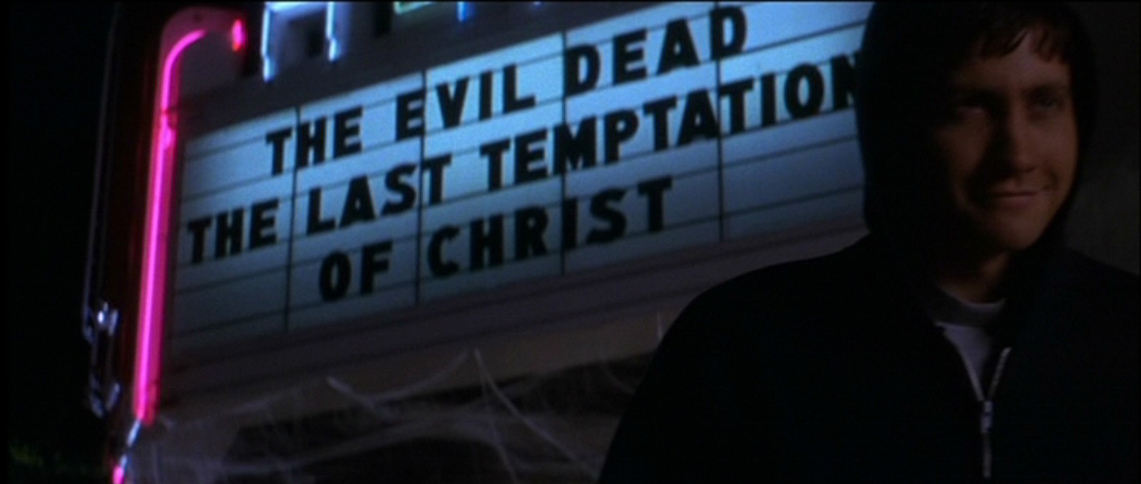 Donnie leaves the movie theater showing 'The Evil Dead' and 'The Last Temptation of Christ.'