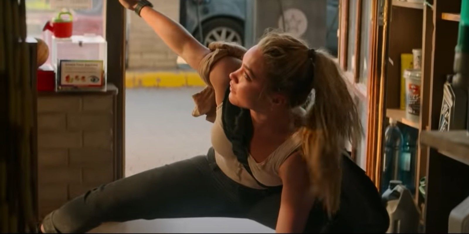 Florence Pugh as Yelena Belova, mimicking Natasha's iconic "Black Widow" pose in a roadside store in Black Widow (2021).