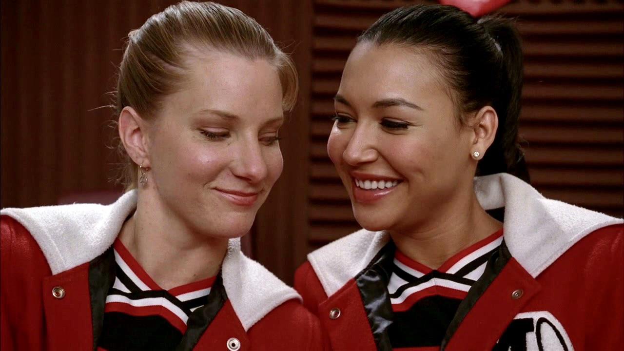 Brittany S. Pierce and Santana Lopez smiling at one another in Glee (2009-2015). 