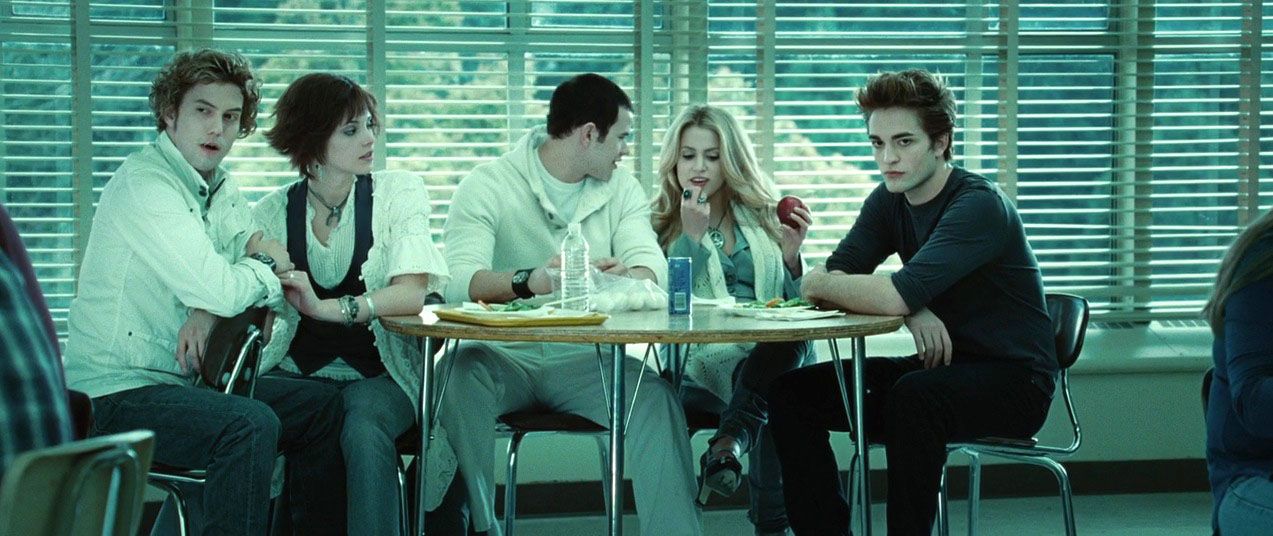 From left to right, sitting at a table in the cafeteria in 'Twilight' (2008): Jackson Rathbone as Jasper Hale, Ashley Green as Alice Cullen, Kellan Lutz as Emmett Cullen, Nikki Reed as Rosalie Cullen, and Robert Pattinson as Edward Cullen.