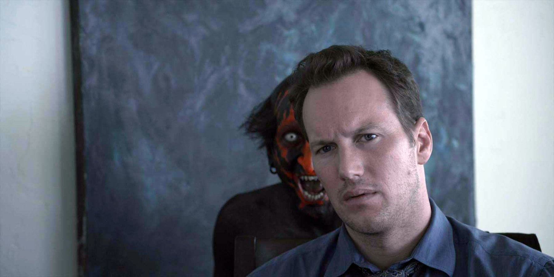 Josh Lambert (Patrick Wilson) stares off at something while the Lipstick-Face Demon stands behind him.
