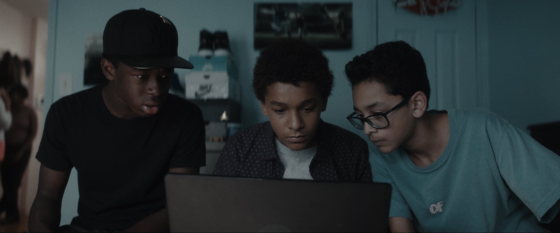 Bobby Carter (Gerald Jones III), Miguel Martinez (Jaden Michael), and Luis Acosta (Greogry Diaz IV) surround a laptop.