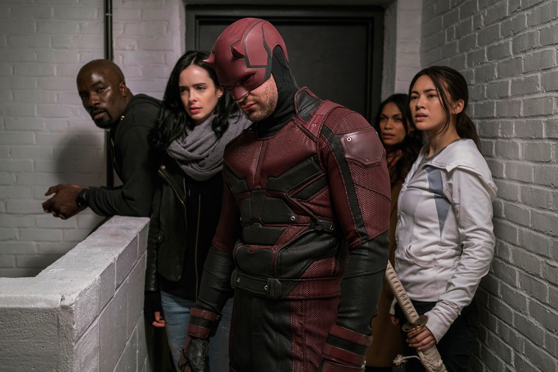 Luke Cage, Jessica Jones, Daredevil, Claire Temple, and Colleen Wing pause in a corridor on Marvel's Defenders