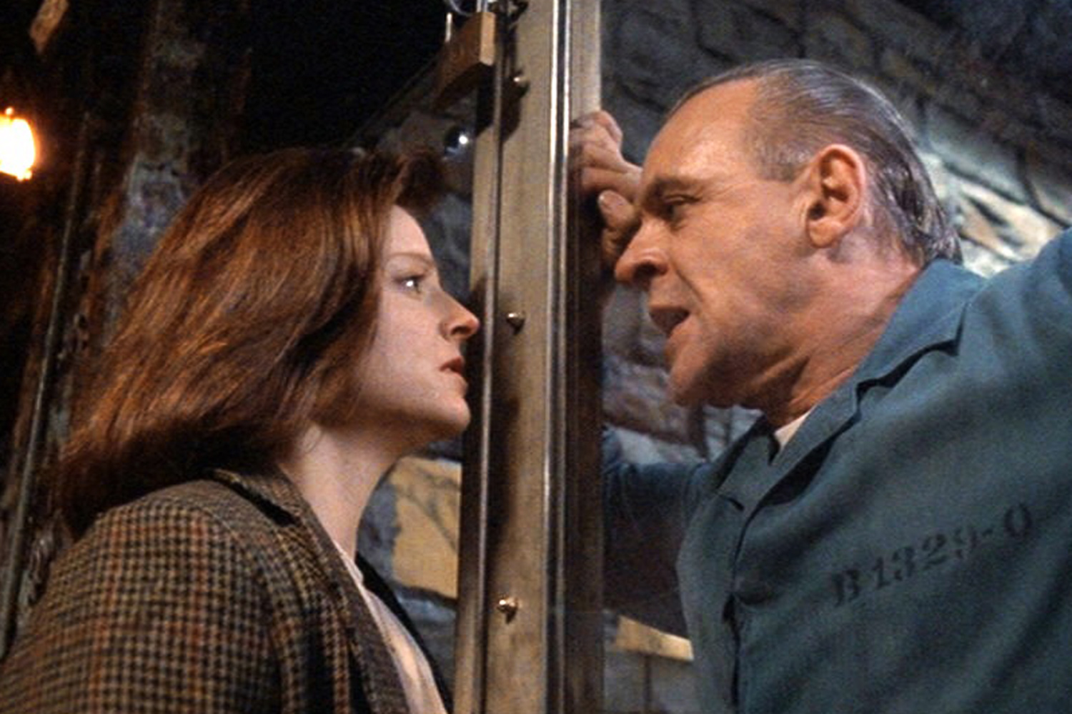 Clarice Starling (Jodie Foster) and Hannibal Lecter (Anthony Hopkins) are face-to-face with Hannibal's cell separating the two.