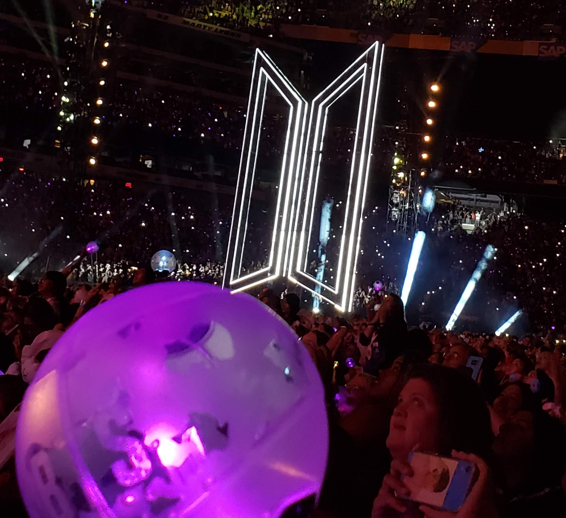 A fantaken photo of her lightstick which is shaped like a sphere where the concert crowd is featured behind it.