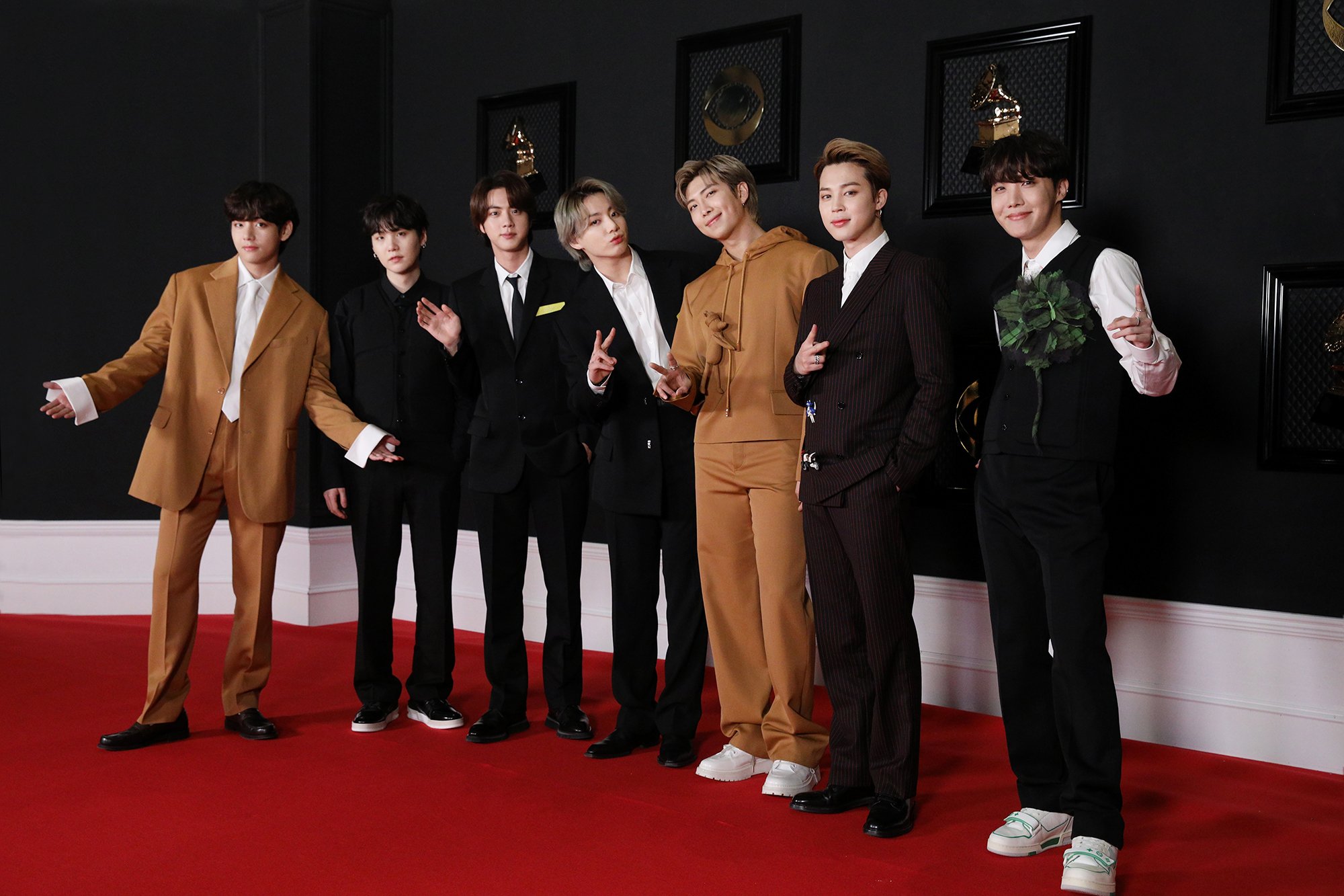All seven members of BTS, all dressed in suits, taking photos on the red carpet for The Grammys. Their nomination signals the popularity of the Hallyu Wave.