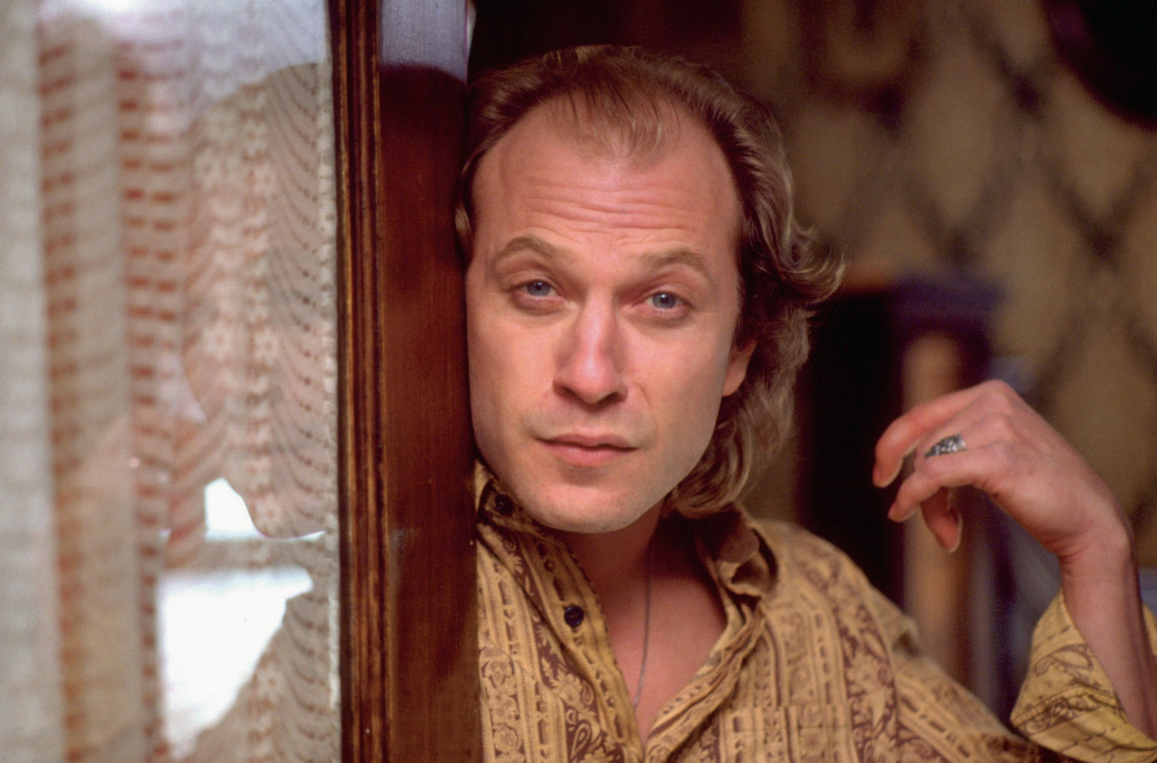 Buffalo Bill (Ted Levine) is standing at the door, looking at someone.