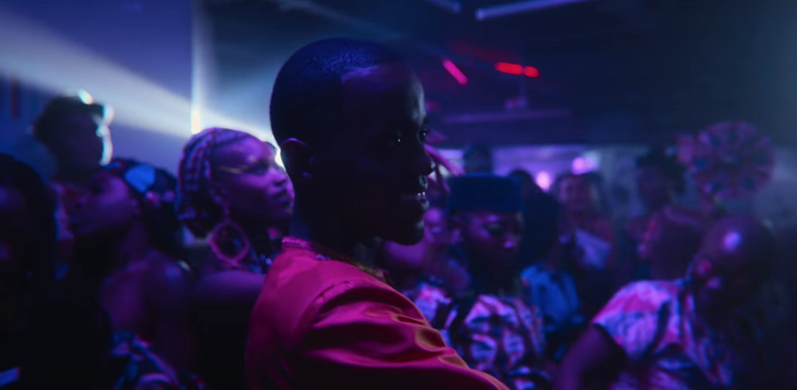 Eric looks around the dance floor of the club as blue light shines over him.  