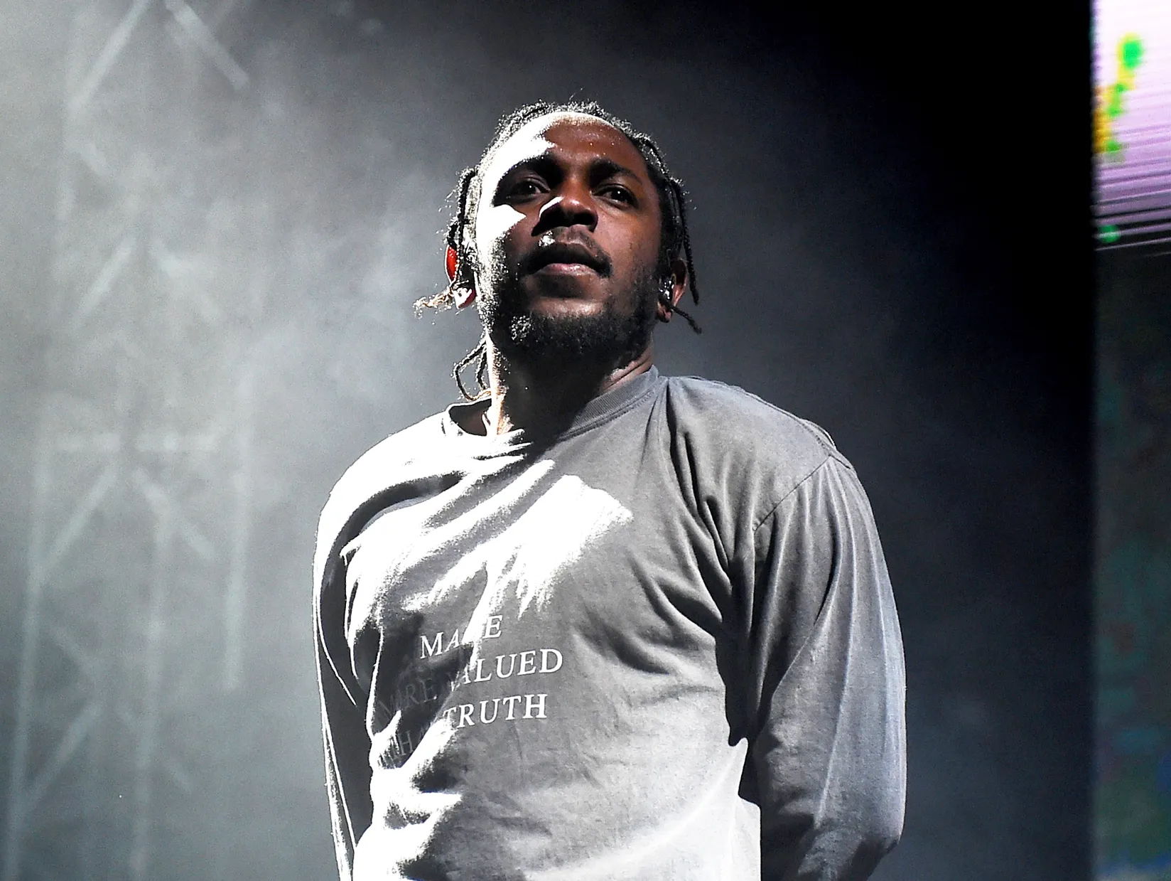 Kendrick Lamar stands on stage. 