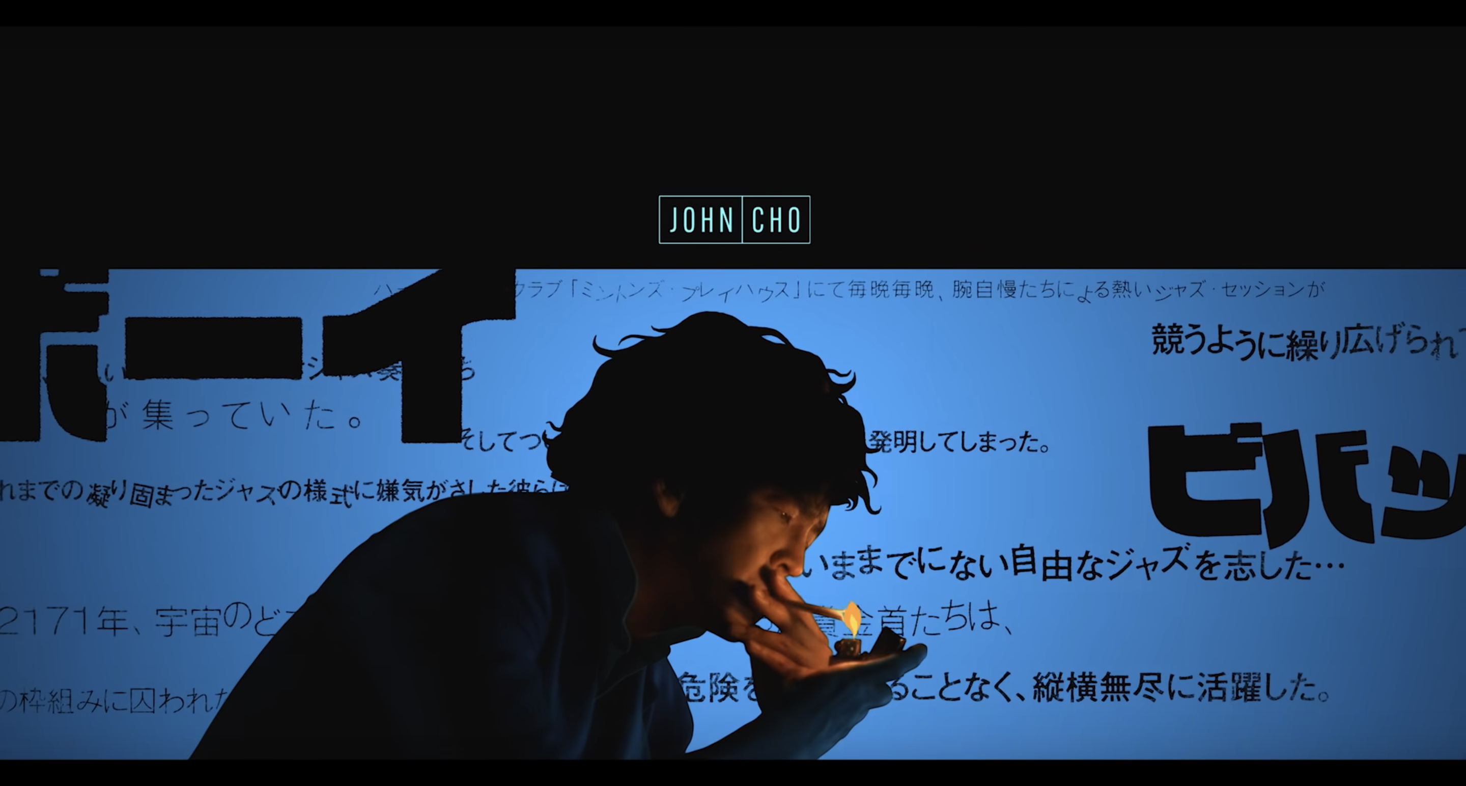 John Cho as Spike Spiegel in the 2021 Cowboy Bebop opening lights a cigarette, shrouded in shadow except for the glow of the lighter.