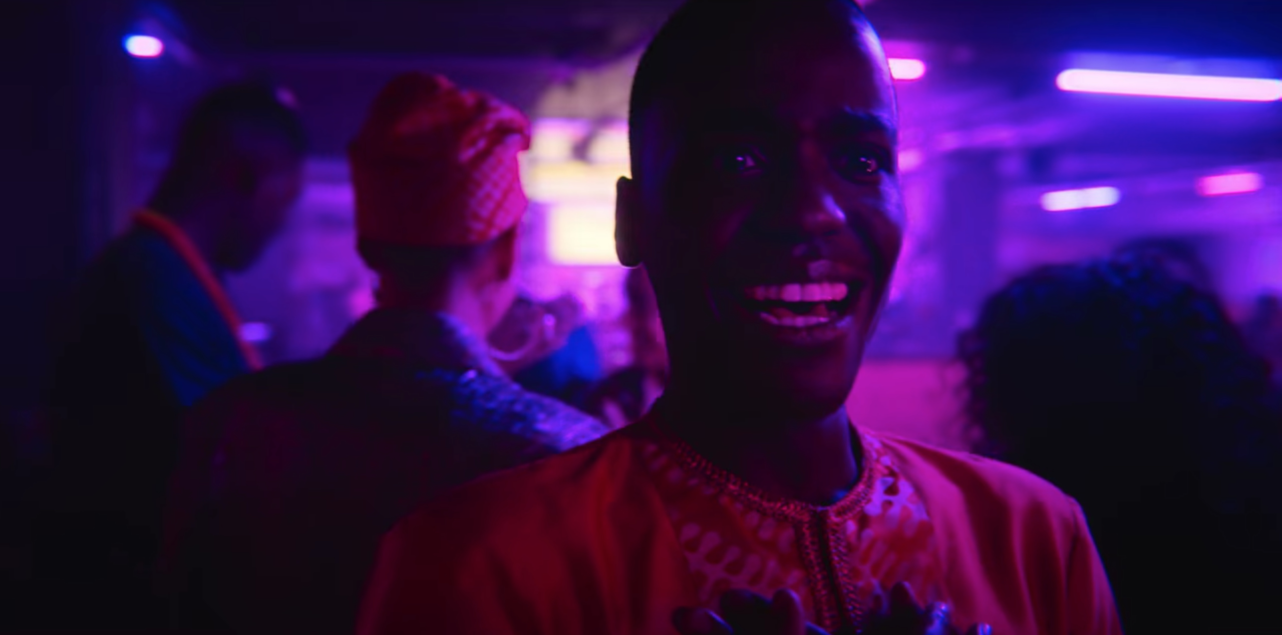 Eric looks around in amazement at the gay bar. Pink and blue lights cast a purple hue over him and the other patrons. 