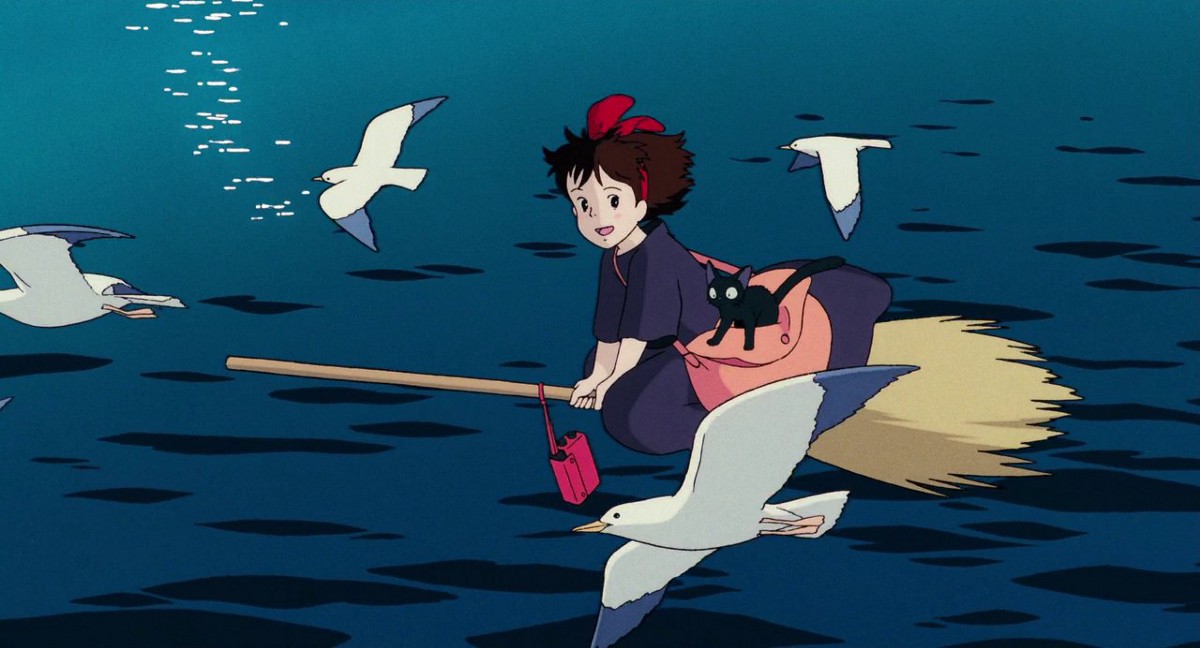 Kiki and Jiji fly on her broomstick over the sea. 