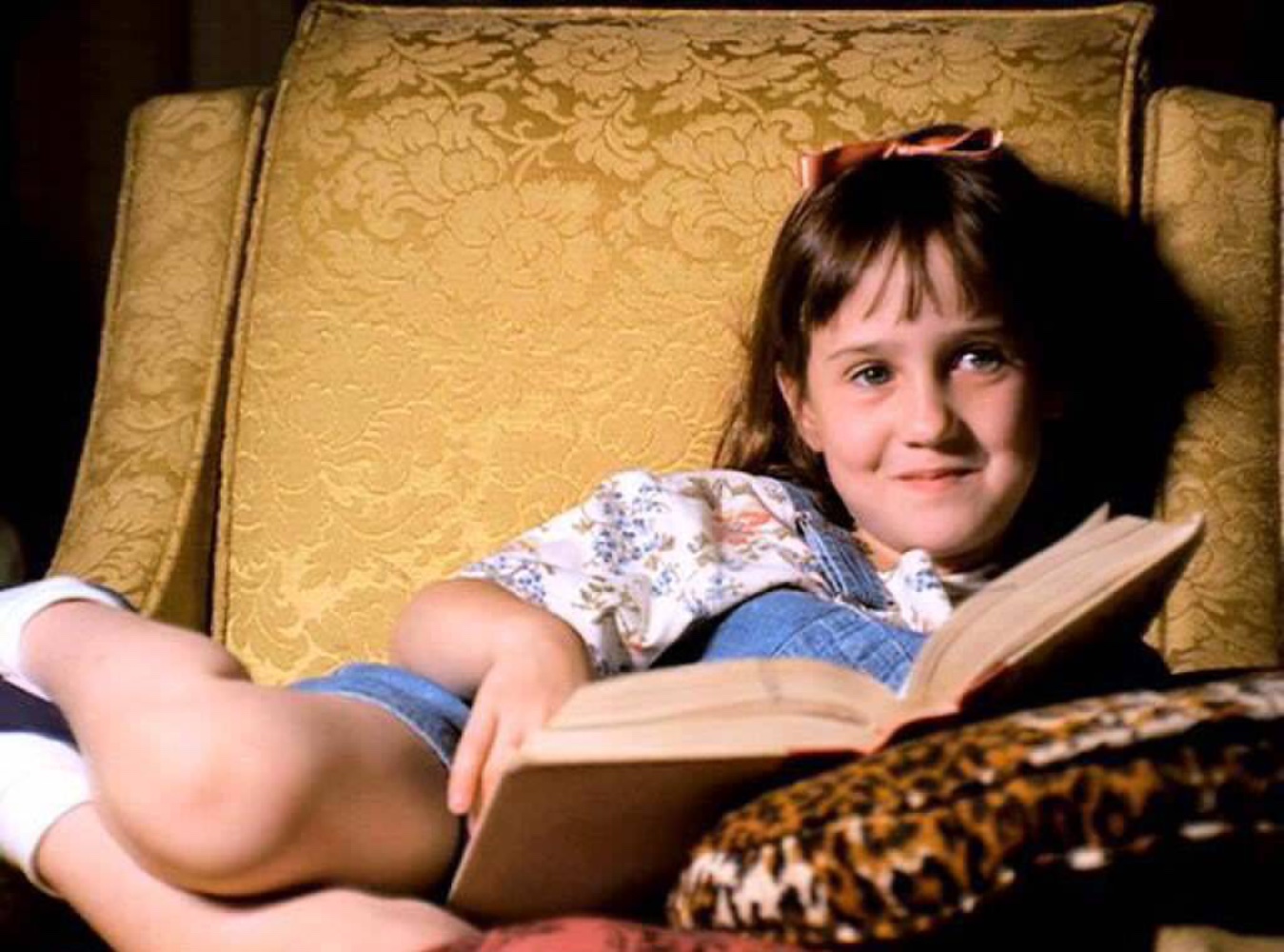 A still from the film of the nerdy protagonist reading a book while sitting under a tree.