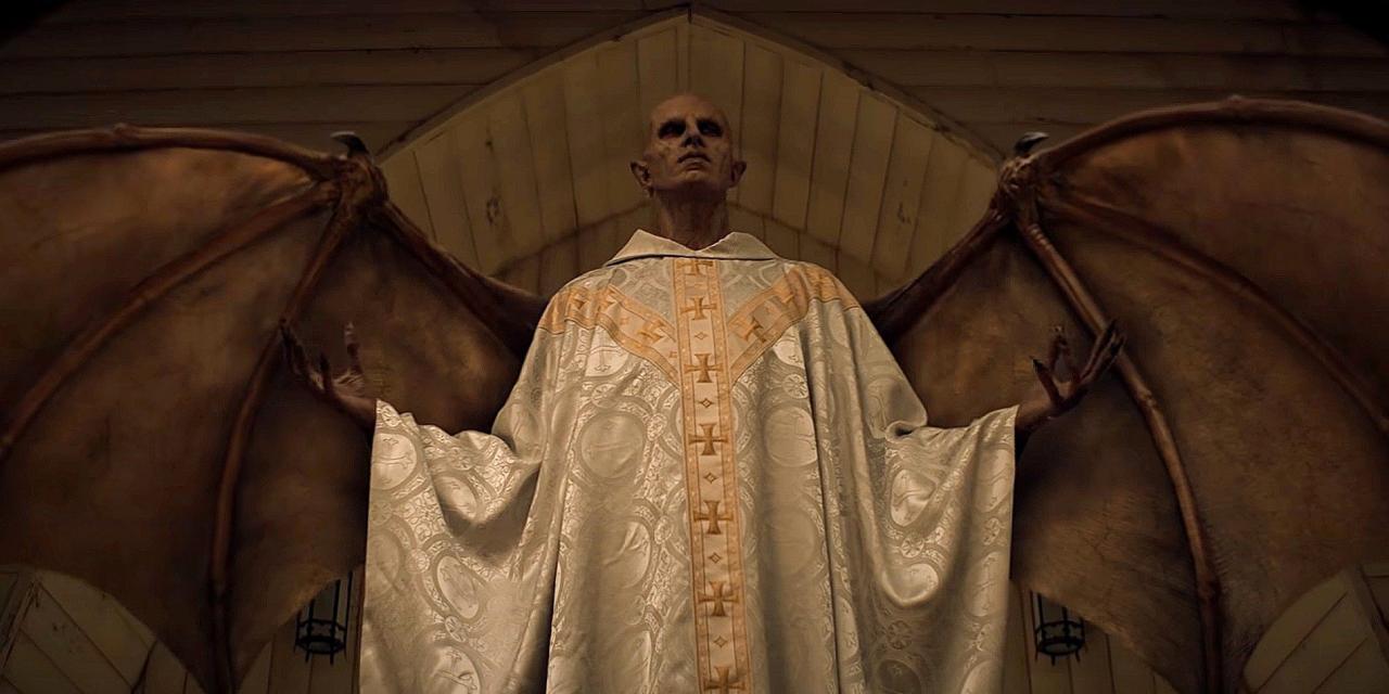 The monster of Midnight Mass stands in priest garb with its wings spread. Midnight Mass. Season 1, Episode 6: "Book VI: Acts of the Apostles". 2021. Netflix Entertainment. 