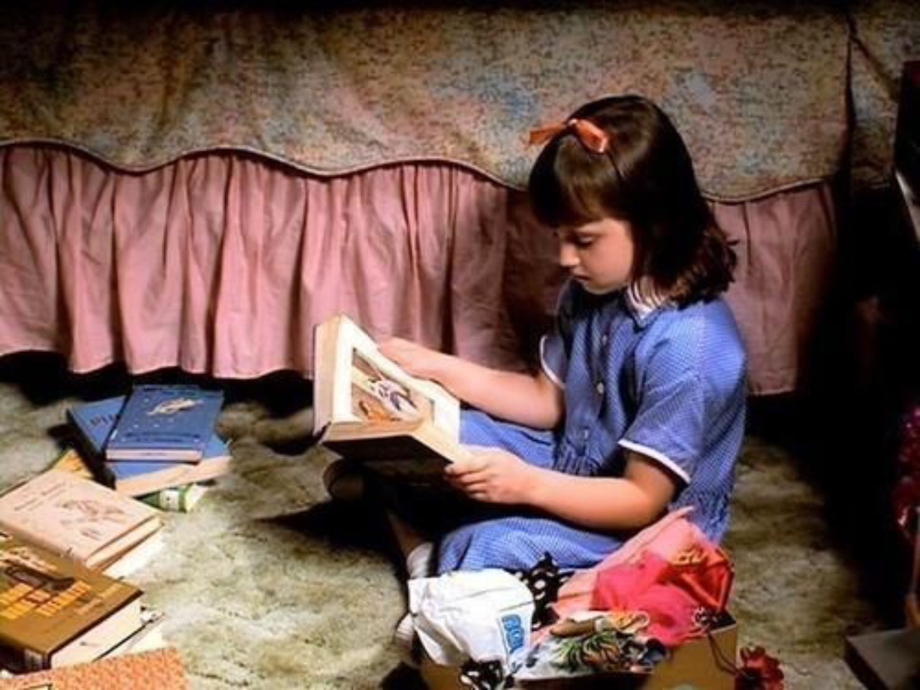 A still from the film of the young protagonist reading literary classic after classic on her bedroom floor.