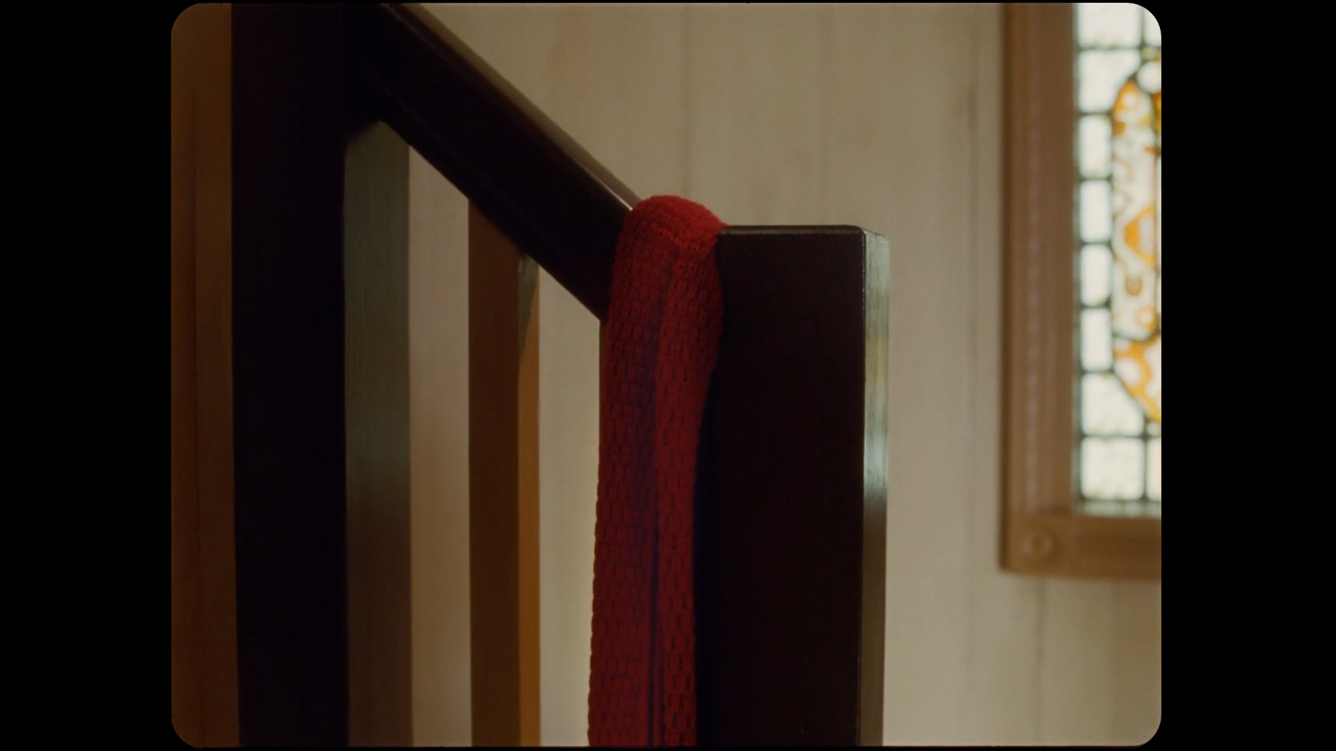 The red, "All Too Well" scarf is left over a banister of a staircase.