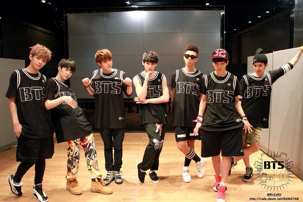 BTS pose in black jerseys that read "BTS."