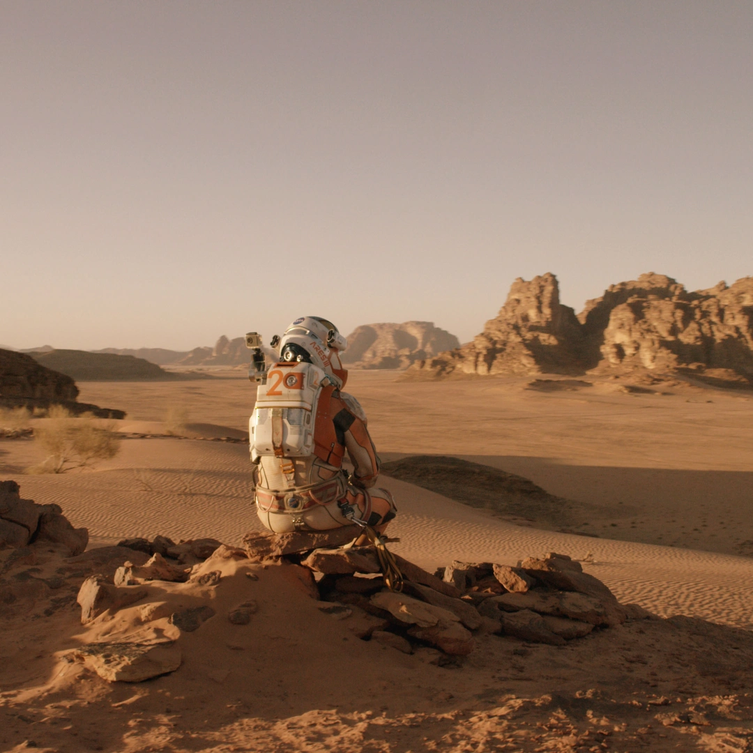 Mark Watney (Matt Damon) is sitting and looking out over Mars's empty landscape.