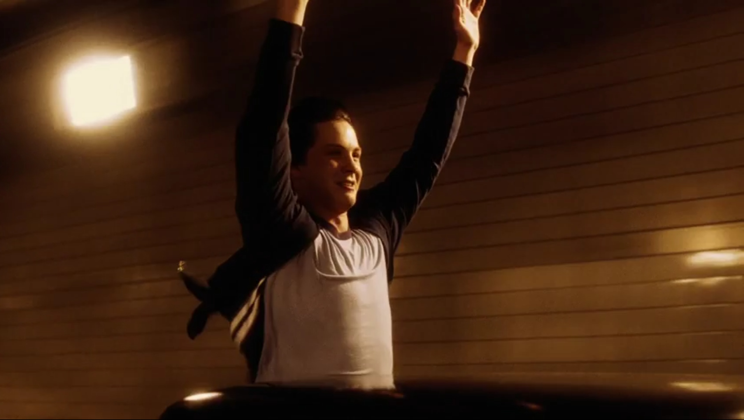 Charlie throws his arms in the air and smiles as he rides through the tunnel in 'The Perks of Being a Wallflower' (2012).