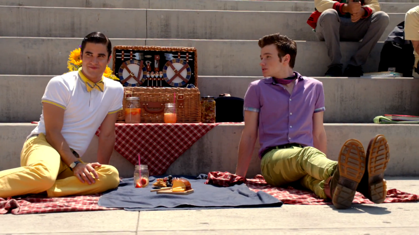 Blaine Anderson (Darren Criss) and Kurt Hummel (Chris Colfer) sit on the ground with a picnic spread out between them. Glee. (2009-2015). Fox.