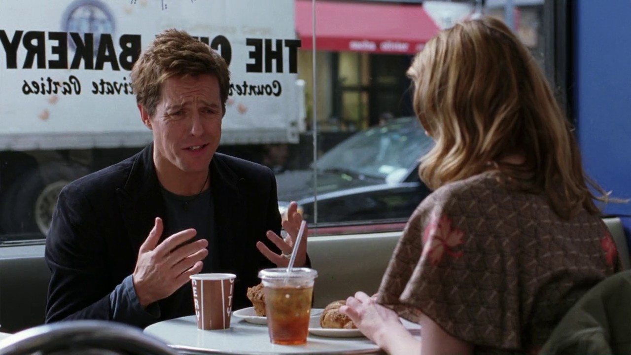 Hugh Grant as Alex Fletcher and Drew Barrymore as Sophie Fisher sitting in a cafe together in Music and Lyrics (2007). 