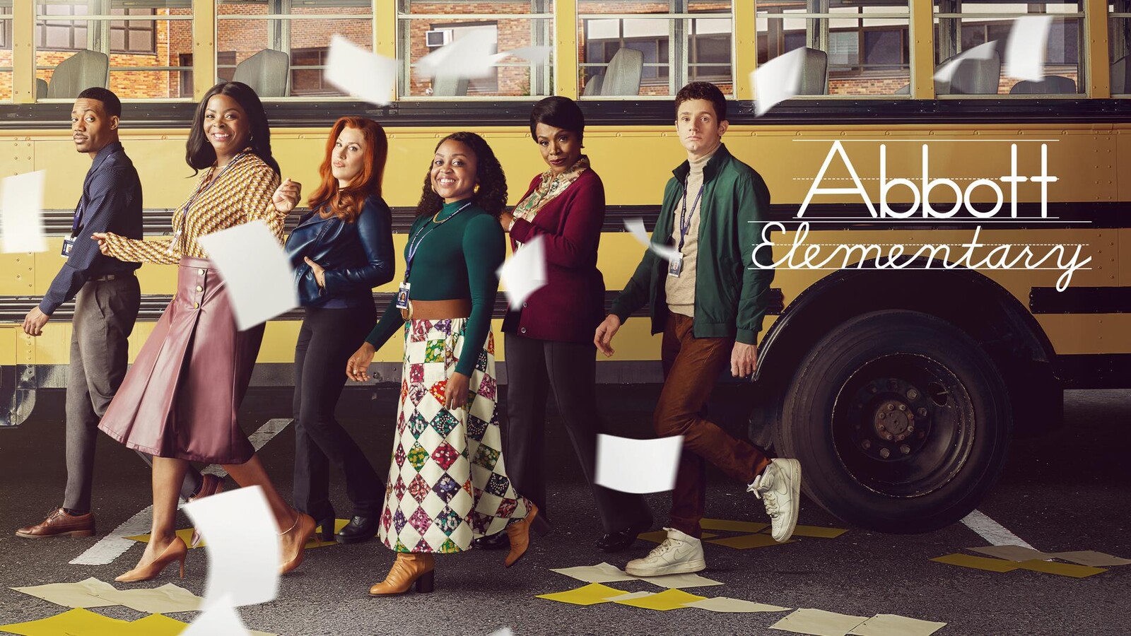 The leads of 'Abbott Elementary' walking past a school bus behind them.