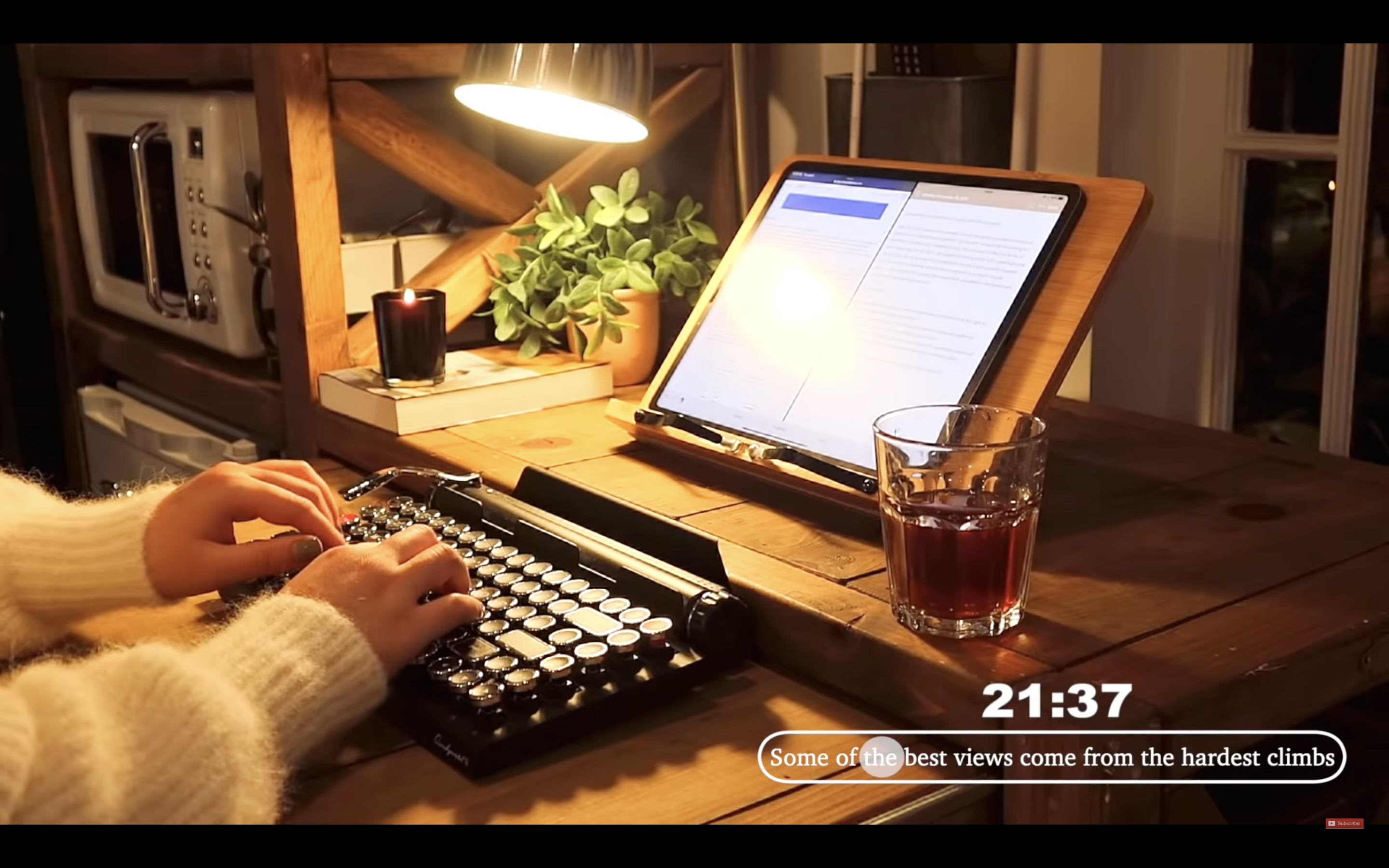 Screenshot of a "study with me" video from The Sherry Formula. A person (face not visible) is using a typewriter-style keyboard with a tablet at night. The timer at the bottom right corner reads "21:37" and includes the quote "Some of the best views come from the hardest climbs". 