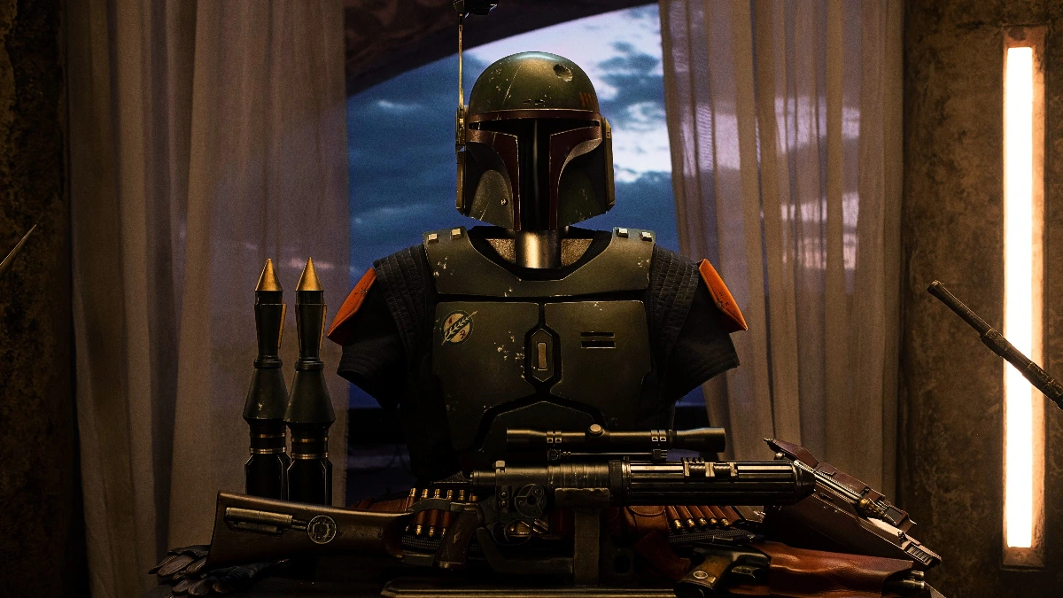 The green armor of Boba Fett is mounted on a stand. A blaster lies in front of it, along with other weapons.