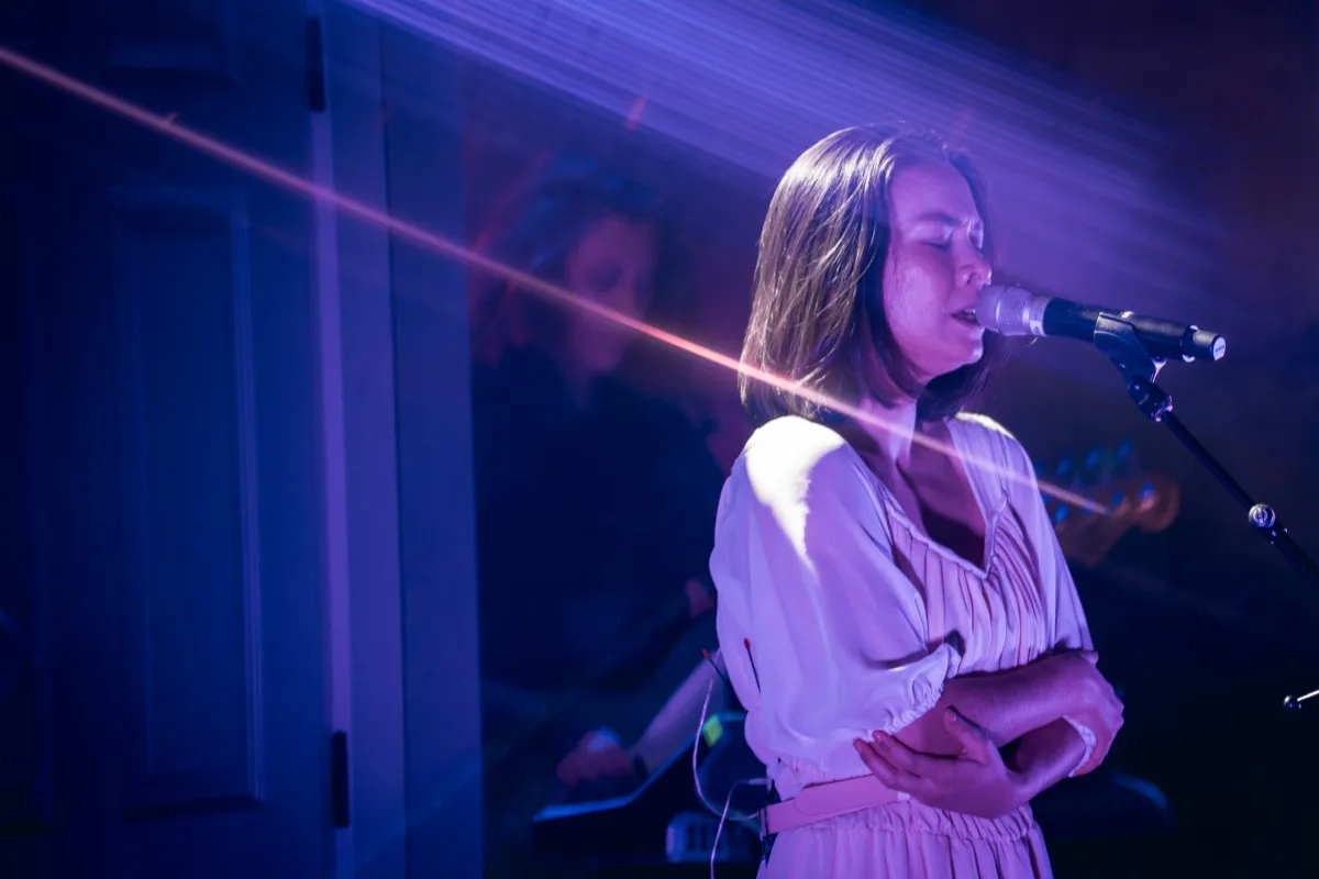 Mitski sings into a microphone at one of her 2022 tour stops. (Willingham, Jones. Melodic Magazine. Feb. 2022.).