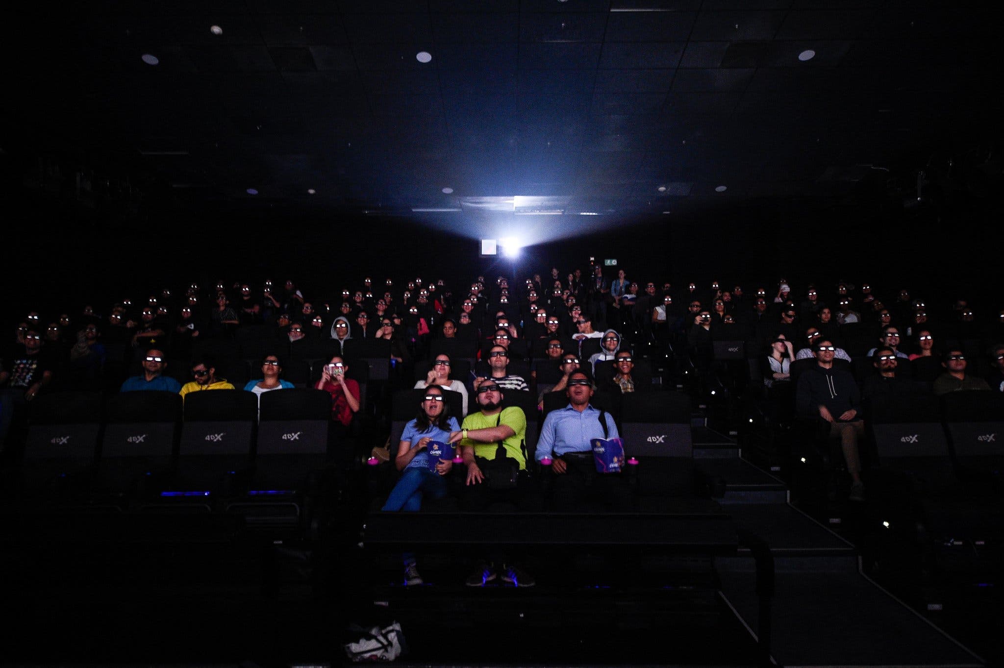 In a darkened movie theater, moviegoers react as they watch Marvel's "Avengers: Endgame" (2019).